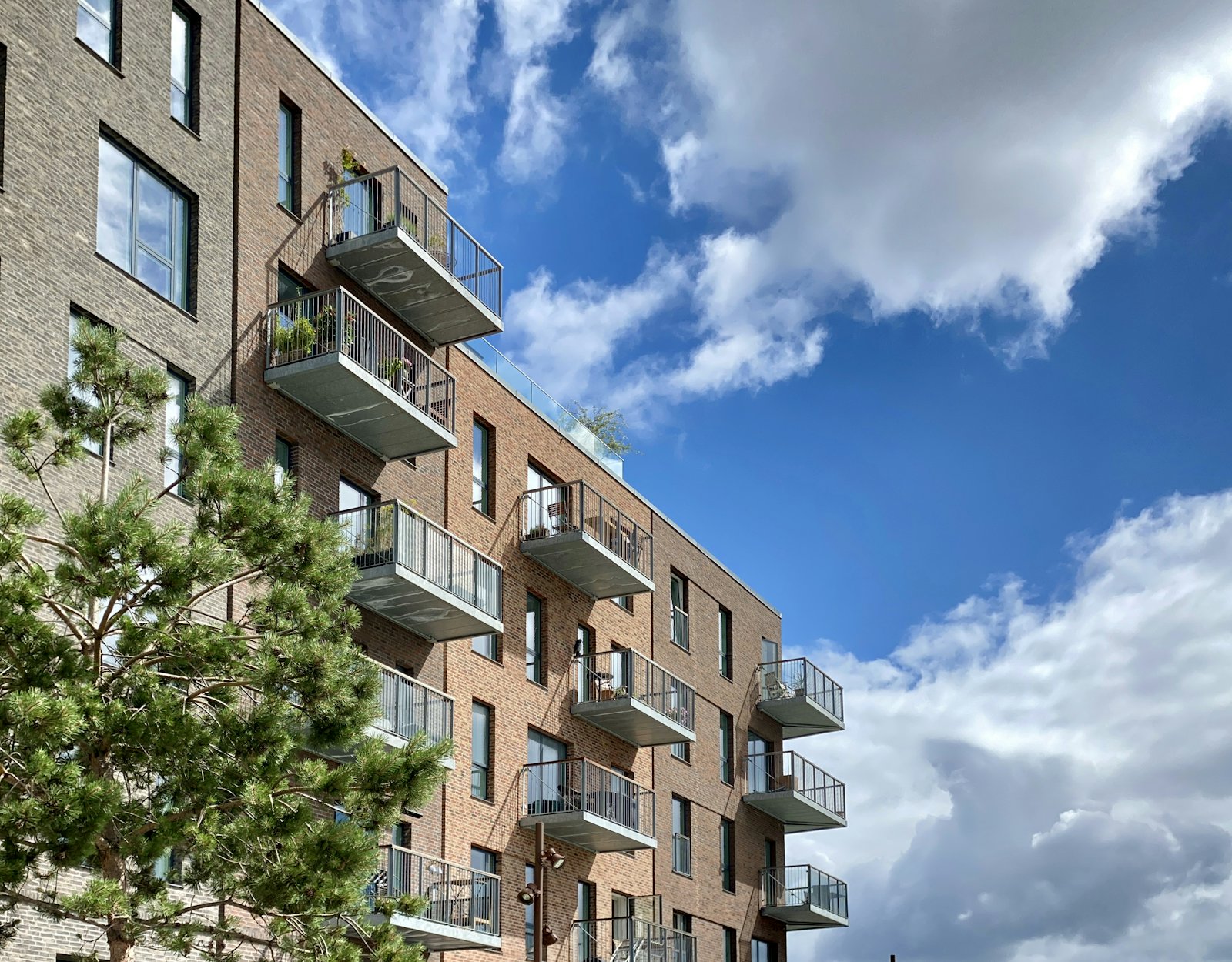 Brick apartment building with balconies and a tree