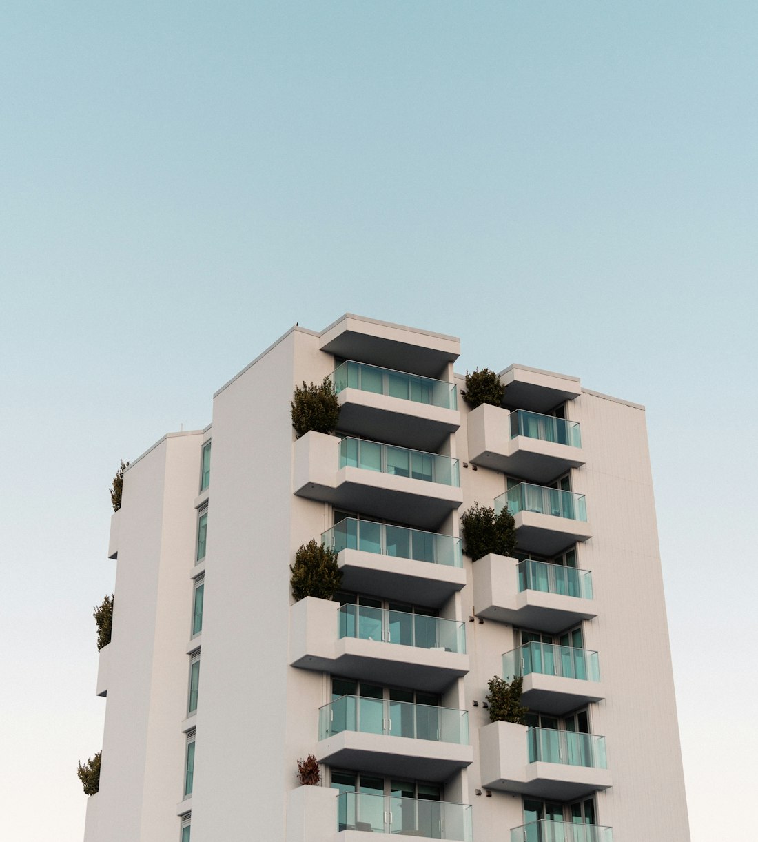 Modern white apartment building with plants on the balconies