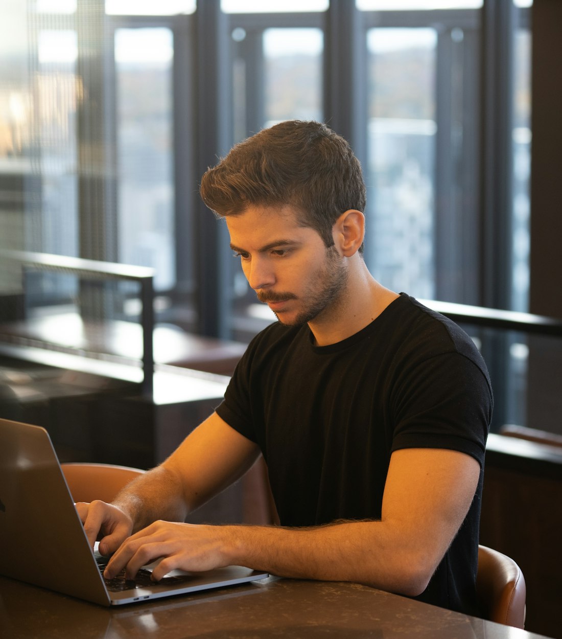 Man working on a laptop by a window