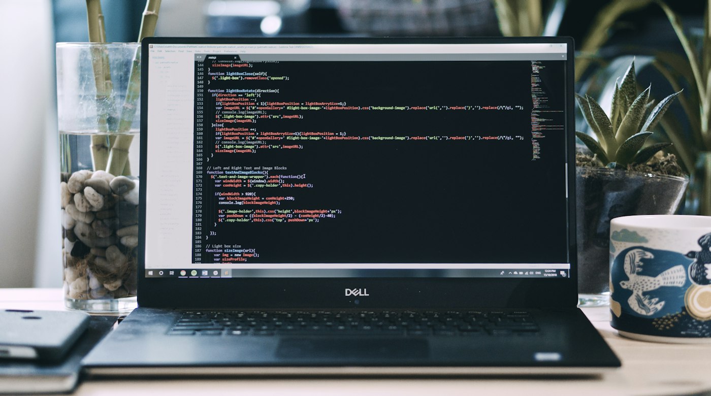 Laptop showing code on a desk beside a coffee cup